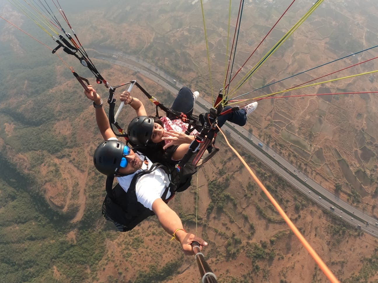 Tandem paraglider flying over Kamshet with Pawna Lake in the distance
