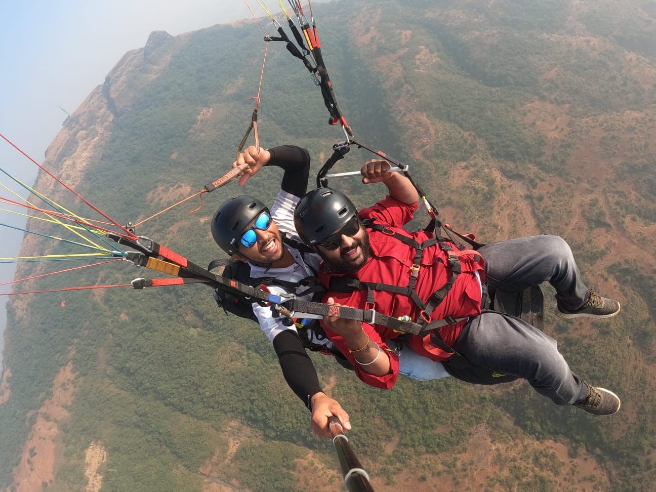 Tandem paraglider ascending from Kamshet launch point at Tower Hill