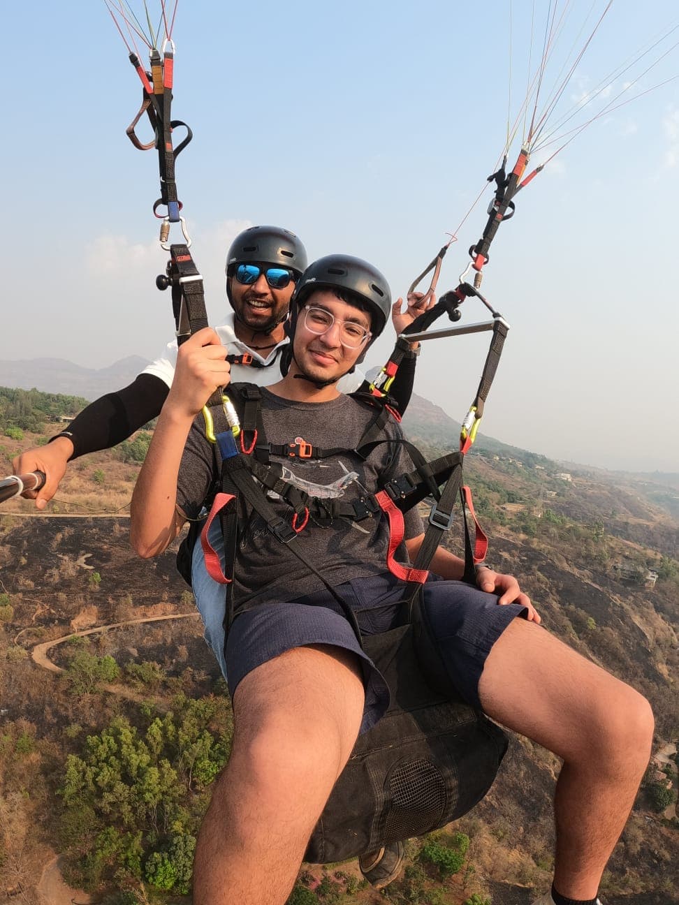 Vertical GoPro shot of paragliding passenger over Kamshet fields