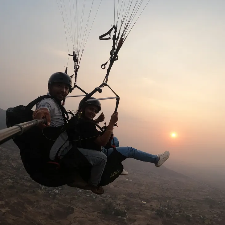 Tandem paragliding passenger and pilot flying over Kamshet farmland