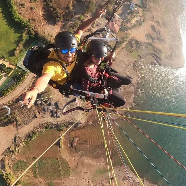 Acro tandem paraglider performing a steep spiral above the Kamshet hills