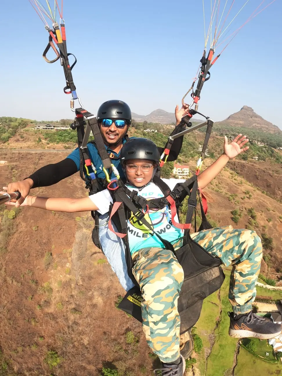 Paraglider soaring above the Sahyadri hills near Kamshet with Pawna Lake in the distance